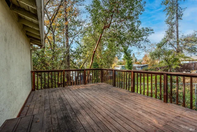 a balcony with wooden floor and trees