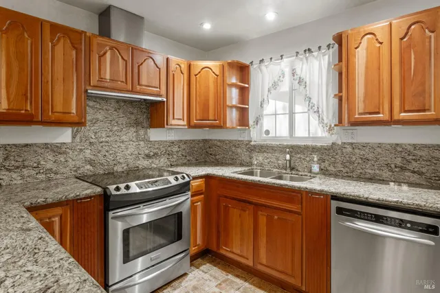 a kitchen with granite countertop a sink stove and cabinets