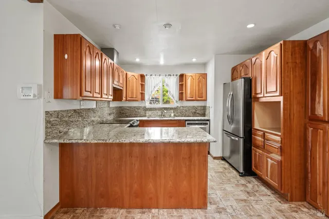a kitchen with stainless steel appliances granite countertop a refrigerator a sink and a stove