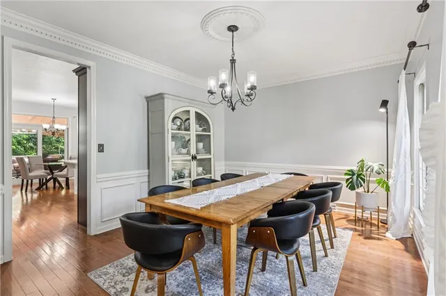 a open kitchen with stainless steel appliances granite countertop a stove a refrigerator a kitchen island a dining table and chairs with wooden floor