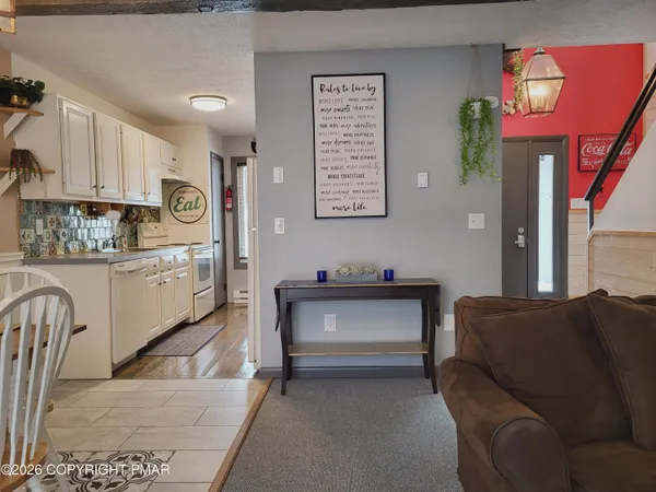 a living room with stainless steel appliances furniture a rug and a kitchen view