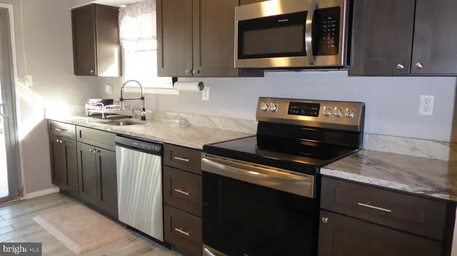 a kitchen with stainless steel appliances granite countertop a sink stove and microwave