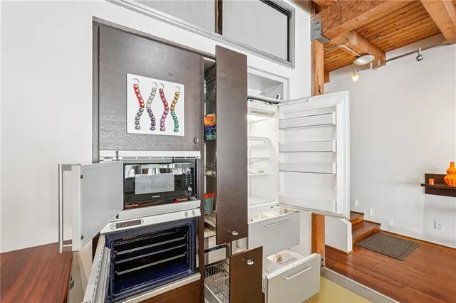 a kitchen with a table chairs refrigerator and wooden floor