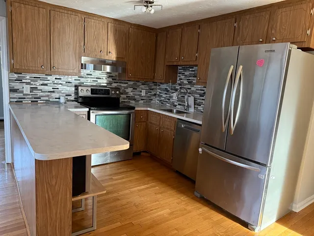 a kitchen with stainless steel appliances granite countertop a refrigerator a sink and a stove