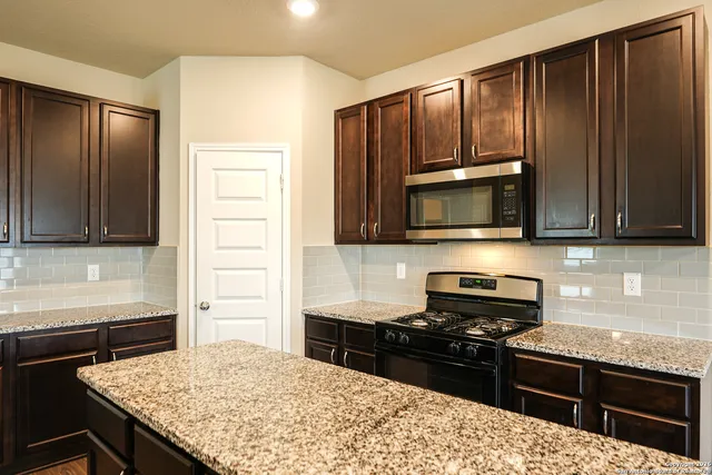 a kitchen with granite countertop wooden cabinets and stainless steel appliances
