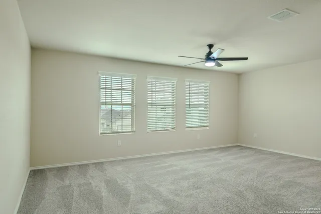 an empty room with chandelier fan and windows