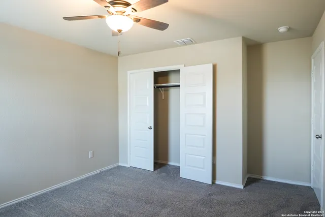 an empty room with closet and a chandelier fan