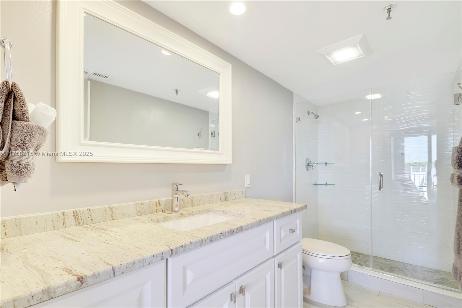 1300 Florida A1A, Unit 325 Jupiter, FL 33477 - Photo 23 of 44 a bathroom with a granite countertop sink a toilet and a mirror