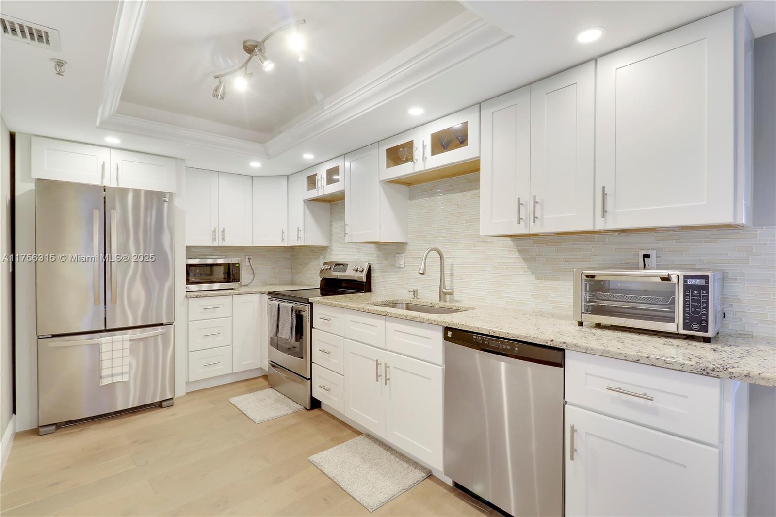 1300 Florida A1A, Unit 325 Jupiter, FL 33477 - Photo 4 of 44 a kitchen with white cabinets and stainless steel appliances