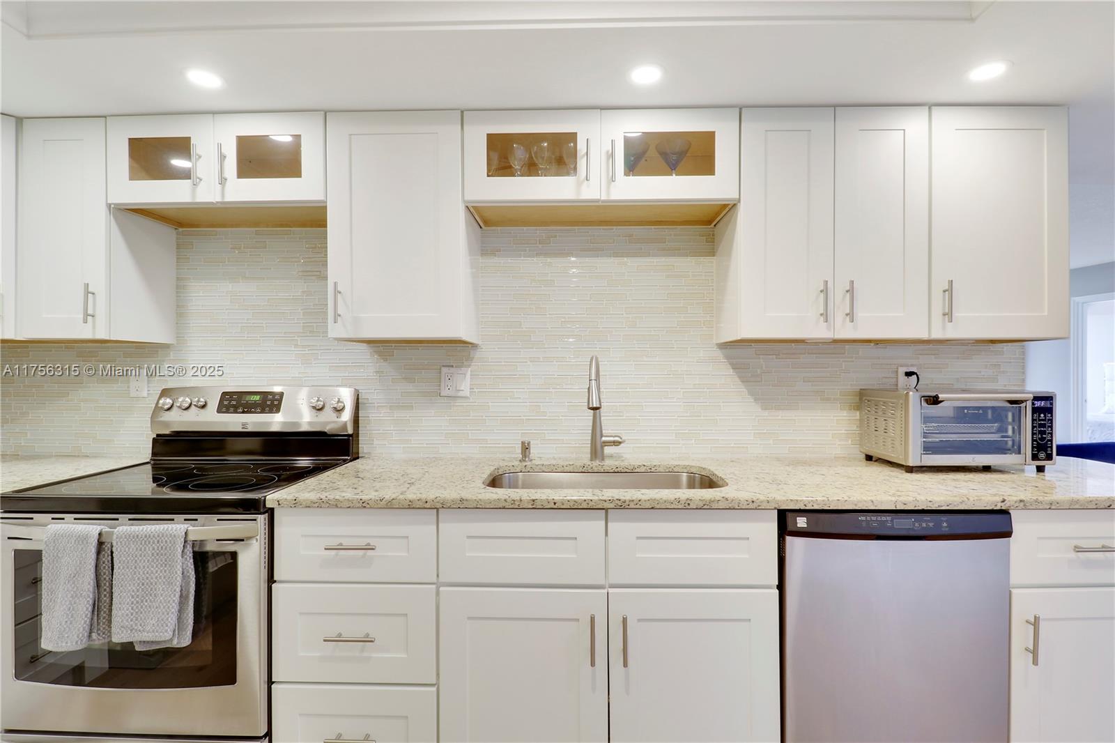 1300 Florida A1A, Unit 325 Jupiter, FL 33477 - Photo 5 of 44 a kitchen with granite countertop white cabinets and white appliances