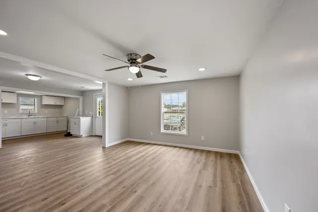 a view of an empty room with a window and wooden floor