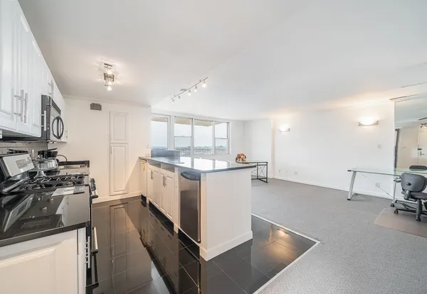 a kitchen with stainless steel appliances a stove a sink a refrigerator and white cabinets