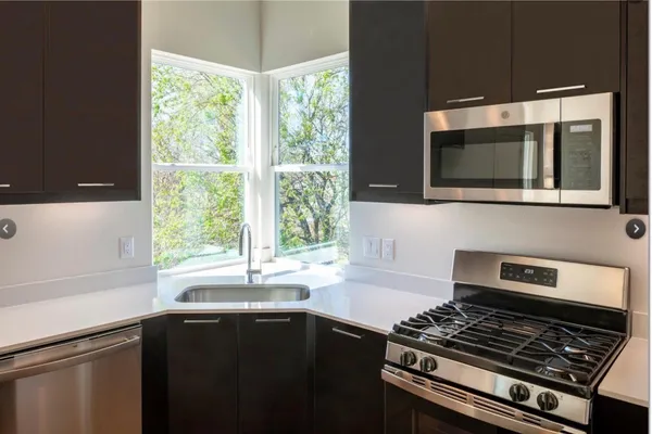 a living room with stainless steel appliances kitchen island granite countertop a refrigerator a sink a stove a dining table and chairs