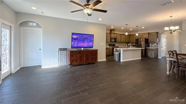 a open kitchen with stainless steel appliances kitchen island granite countertop a refrigerator a stove a sink a dining table and chairs with wooden floor