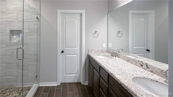 a bathroom with a granite countertop double vanity sink and mirror