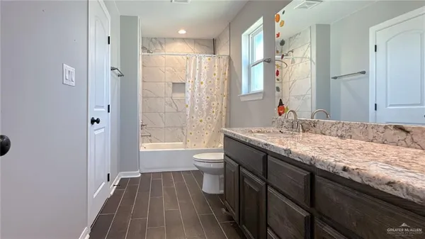 a bathroom with a granite countertop sink toilet a large mirror a vanity and shower