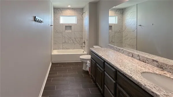 a bathroom with a granite countertop sink a toilet and shower