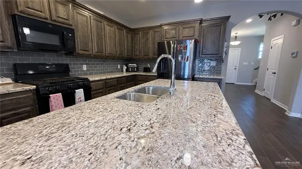 a kitchen with granite countertop a sink and a stove top oven