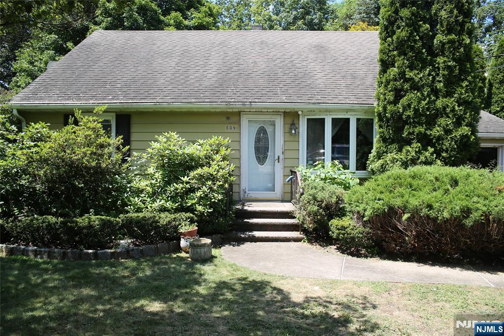 a view of a house with a yard plants and large tree
