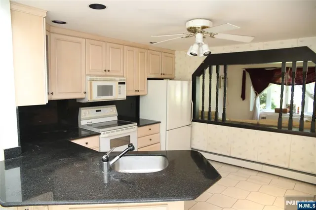 a kitchen with granite countertop a stove a sink and a refrigerator