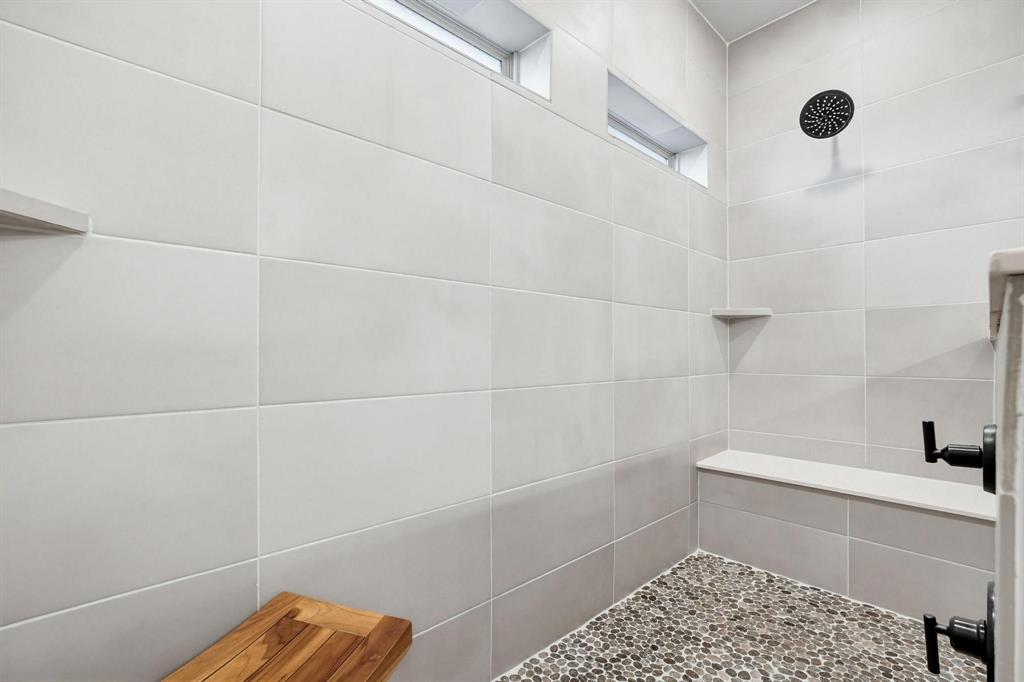 9341 Loggerhead Way Fort Worth, TX 76118 - Photo 24 of 35 Tiled shower with pebble flooring, integrated bench seating, built-in shelf, and transom windows