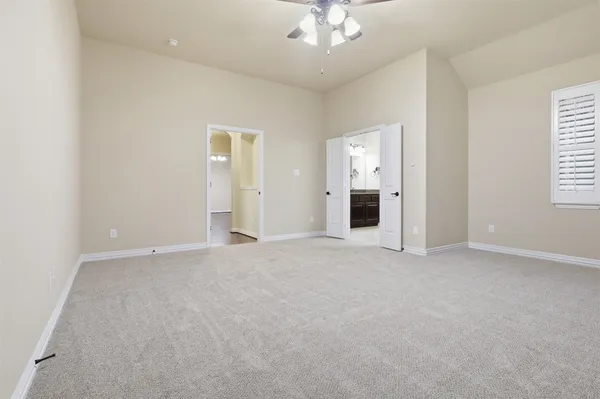 an empty room with chandelier fan and windows