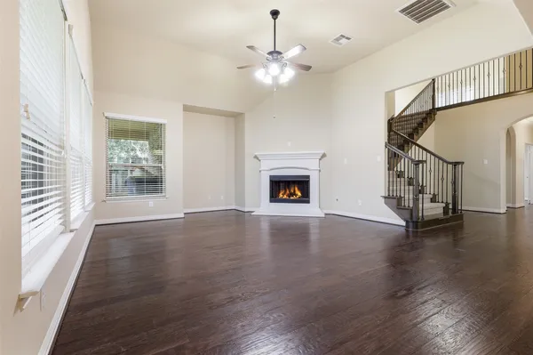 a view of an empty room with wooden floor fireplace and a window