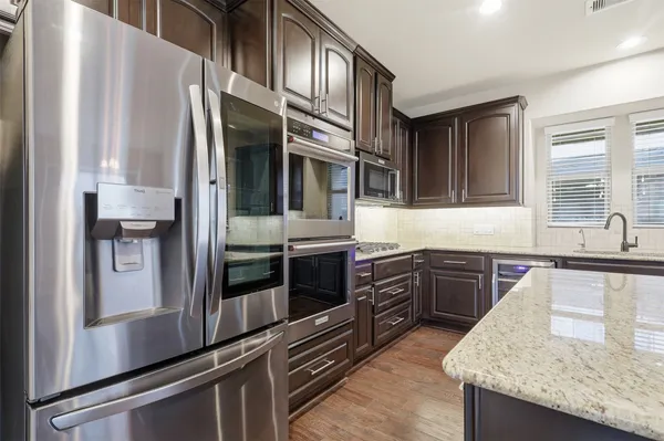 a kitchen with stainless steel appliances granite countertop a refrigerator a stove and a sink with wooden floor