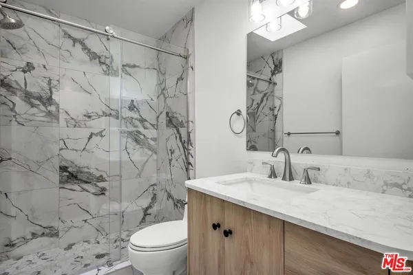 a bathroom with a granite countertop sink a toilet and a mirror