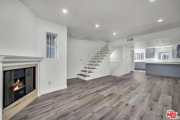 a view of an empty room with wooden floor fireplace and a window