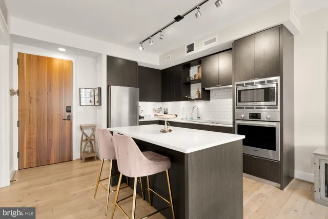 a kitchen with stainless steel appliances kitchen island a table chairs and a refrigerator
