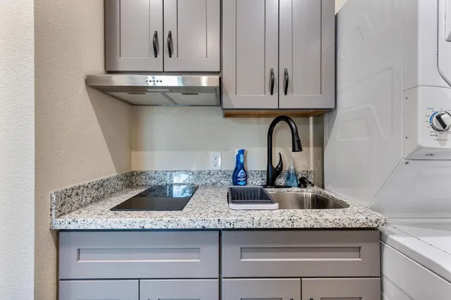 a kitchen with granite countertop white cabinets and sink