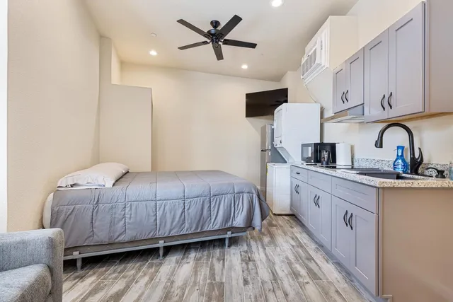 a bedroom with a bed and a dresser with wooden floor