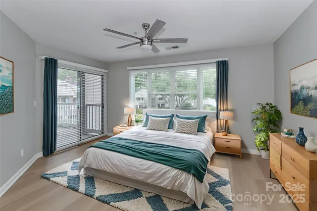 a bedroom with a balcony a bed a chandelier and a large window