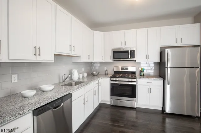 a kitchen with granite countertop white cabinets and stainless steel appliances
