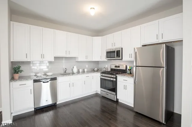 a kitchen with cabinets stainless steel appliances a sink and wooden floor