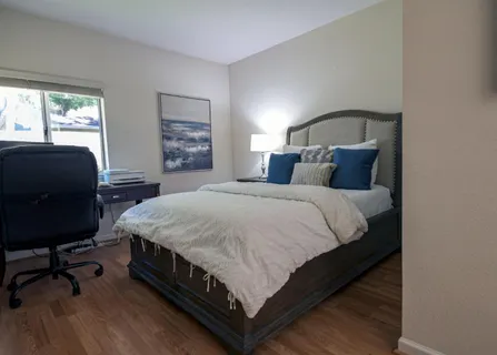 a bedroom with a bed a chair and a large window