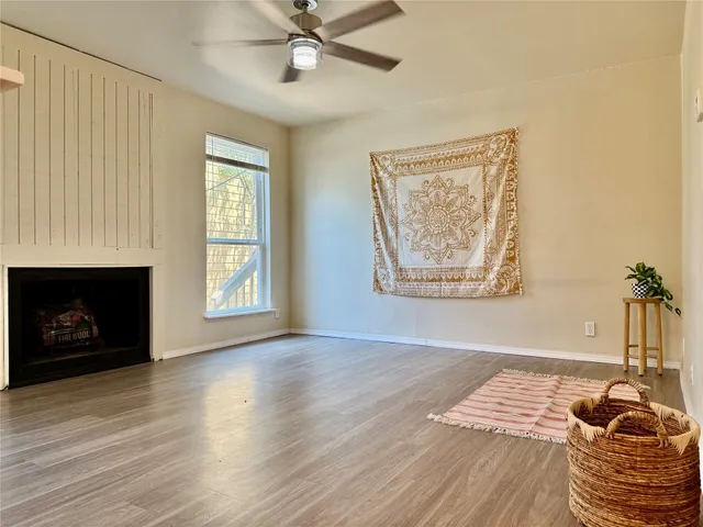 a view of an empty room with wooden floor fireplace and a window