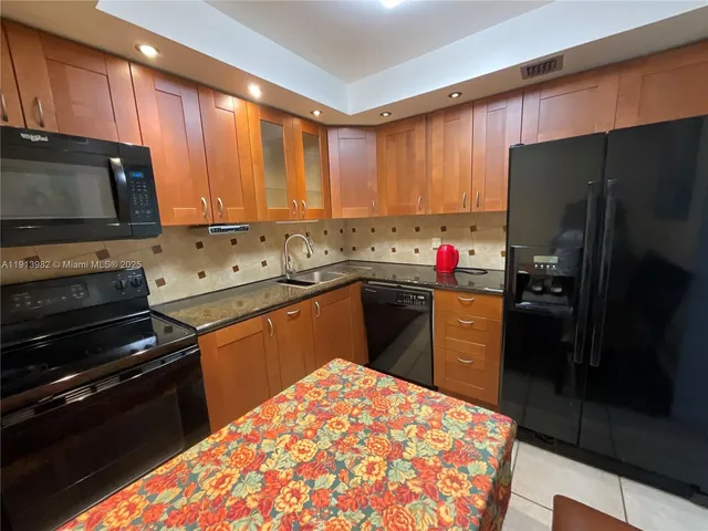a kitchen with stainless steel appliances kitchen island granite countertop a refrigerator and a stove top oven