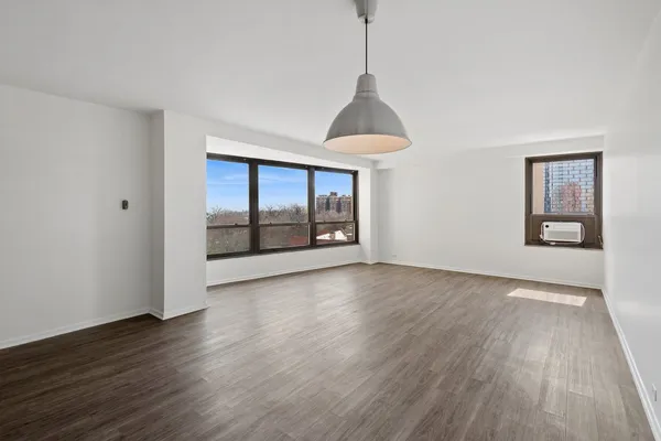 a view of an empty room with window and wooden floor