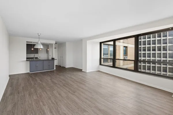 a view of an empty room with a kitchen and wooden floor