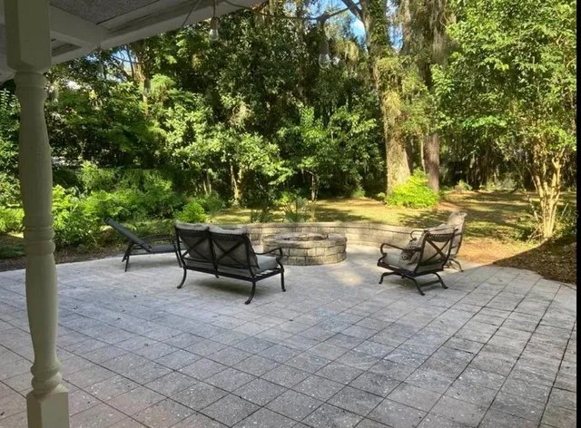 a view of a patio with table and chairs potted plants and large tree