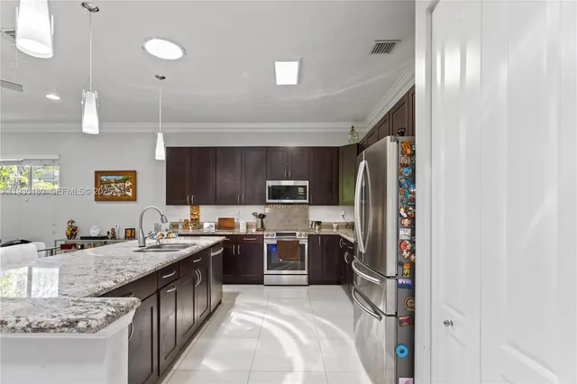 a kitchen with stainless steel appliances kitchen island granite countertop a sink and a wooden floors