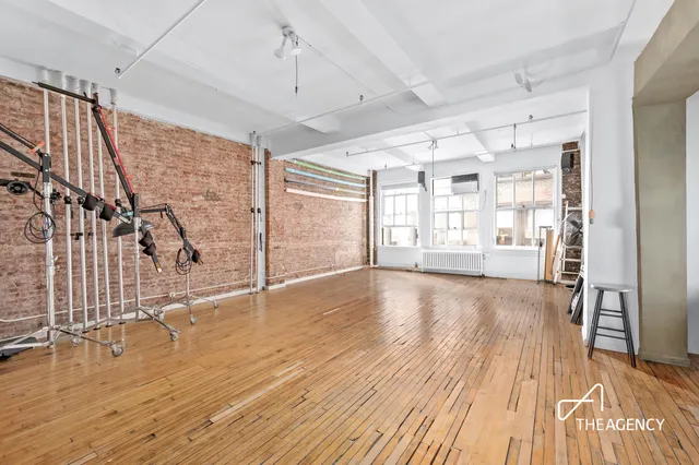 a living room with stainless steel appliances furniture a large window and wooden floor