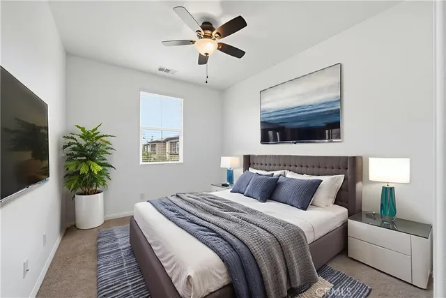 a bedroom with a large bed a flat tv screen and a potted plant