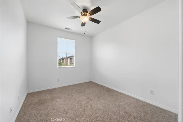an empty room with a window and a fan