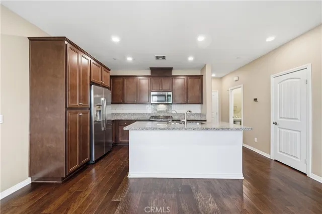 a kitchen with stainless steel appliances granite countertop a refrigerator a stove and a wooden floors