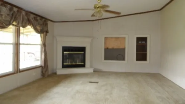 a view of an empty room with a window and kitchen view