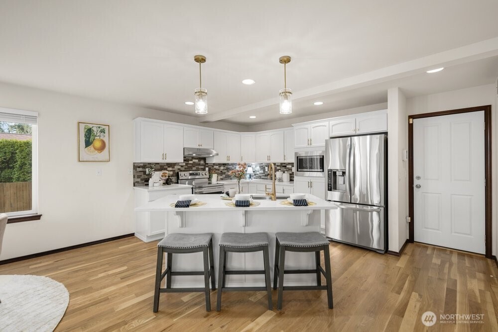 1152 Johnson Street Monroe, WA 98272 - Photo 19 of 38 a dining room with stainless steel appliances kitchen island granite countertop a refrigerator a stove a microwave oven with white cabinets and wooden floor