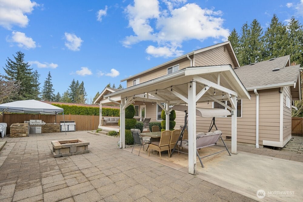 1152 Johnson Street Monroe, WA 98272 - Photo 31 of 38 a view of a patio with a table and chairs under an umbrella with a fire pit and a barbeque